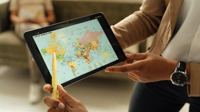 Close-up of hands holding a digital tablet displaying a world map, ideal for educational content.
