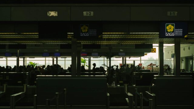 Silhouetted travelers wait at a bustling airport check-in counter, showcasing Saigon Ground Services.