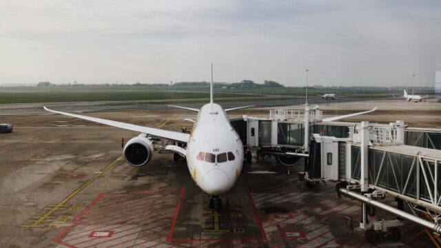 A modern jet airplane docked at an airport terminal gate, ready for boarding on a cloudy day.
